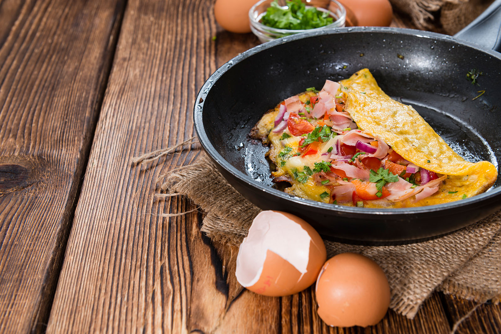 Pan with Ham and Cheese Omelette on rustic wooden background.